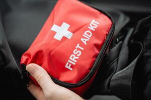 A person confidently holds a bright red first aid kit in their hands, fully prepared to assist anyone in need or to respond quickly and effectively to any emergency situation that may arise photo