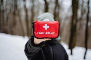 A person is holding up a bright red first aid kit right in front of their face, which makes it the most prominent focal point in this entire scene, capturing everyones attention here photo