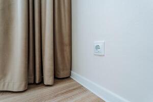 The interior of a bedroom featuring a decorative curtain and an electrical socket conveniently located on the wall, enhancing both functionality and style in the overall design photo
