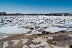 A vast and expansive body of water that is completely covered in a thick layer of ice and snow, with a beautifully structured bridge visible in the background of the scene photo