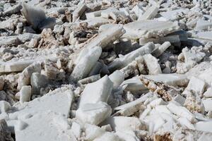 A large, uneven pile of broken pieces of ice lies scattered across the ground, creating a striking and unusual sight that naturally captures the attention of curious passersby nearby photo