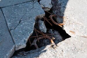 A cracked concrete floor that has a noticeable hole indicates ongoing wear and tear over time, which suggests a significant and prolonged history of environmental impact and distress photo
