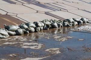 Strategically placed sandbags in a puddle absorb excess moisture, contrasting with the environment and emphasizing their vital role in preventing flooding from heavy rainfall photo