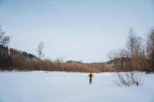 A person is standing alone in the middle of a vast snowcovered field, surrounded by the serene beauty of winters frozen landscape and the chilly air that fills the atmosphere photo