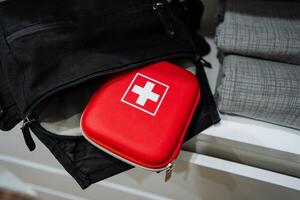 Inside a spacious black bag, there is a bright red first aid kit that is neatly placed. It is ready for use and can be easily accessed in case of an emergency or any medical situation photo