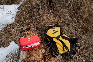 A bright red first aid kit can be found situated right next to a vibrant yellow backpack, ready for any adventure or emergency situation that may arise during your travels photo