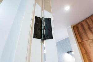 This detailed closeup photo showcases a wellinstalled door hinge on a white door, highlighting the intricate design of household hardware important for functionality and aesthetics