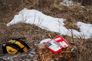 A comprehensive first aid kit is placed on a snowcovered stump, ready to assist in emergencies during outdoor winter activities, ensuring safety and preparedness in the wilderness photo