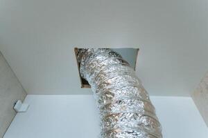 A shiny silver duct protrudes conspicuously from the ceiling, which indicates the presence of a ventilation or piping system that has been installed in the space above our heads photo