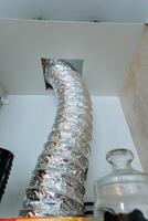 A shiny silver hose is protruding from an opening in the ceiling above, creating an interesting visual element in the room. Its metallic surface reflects light distinctively photo