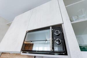 A microwave oven is cleverly and smartly installed within a stylish cabinet located in the center of a contemporary kitchen, significantly enhancing both its functionality and visual appeal photo