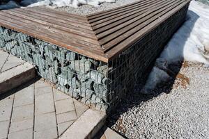 A sturdy and durable wooden bench placed next to a weathered stone wall significantly enhances the outdoor aesthetic and creates a delightful spot for relaxation amid beautiful surroundings photo