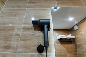 A hair dryer that is securely mounted on the bathroom wall becomes conveniently accessible for anyone who wishes to use it right after enjoying a refreshing shower or a soothing bath photo