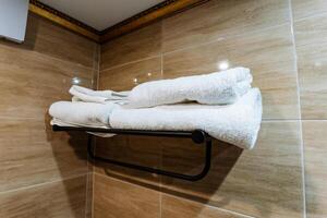 A neatly arranged stack of crisp, white towels is hanging on a polished towel rack in a beautifully designed bathroom, creating a sense of cleanliness and comfort for users photo