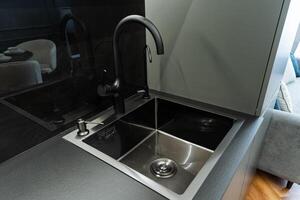 The kitchen features a stylish stainless steel sink that is complemented beautifully by a sleek black faucet, creating a modern and functional area for meal preparation and cleaning photo