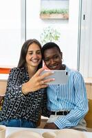 Smiling multiethnic coworkers taking selfie during break in office photo