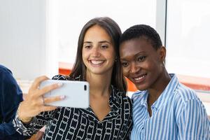 Smiling multiethnic coworkers taking selfie during break in office photo