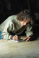 Male carpenter creating sketch in notebook in workshop photo