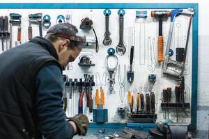 Professional mechanic using spanner while assembling vehicle engine details at workbench photo