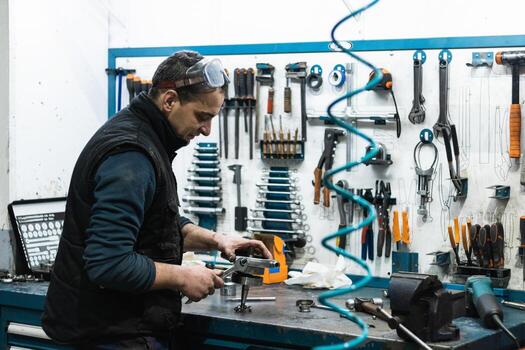 Professional mechanic using spanner while assembling vehicle engine details at workbench photo