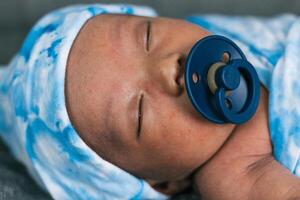 Newborn baby wrapped on soft blanket with pacifier photo