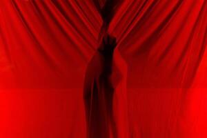 Faceless person hiding behind curtains at night time photo