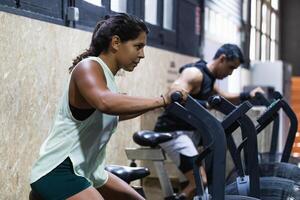 Determined Hispanic sportswoman exercising on air bike photo