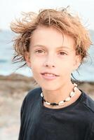 Boy wearing shell necklace looking at camera at beach photo