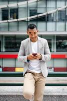Man using smartphone leaning against wall photo
