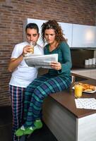 Couple having breakfast and reading newspaper photo