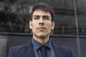 A man in a suit and tie standing in front of a building photo
