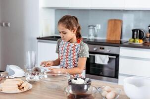A little girl in an apron making cookies photo