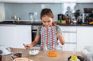 A little girl in an apron making a cake photo