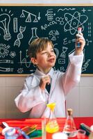 A boy in a lab coat is holding a test tube photo