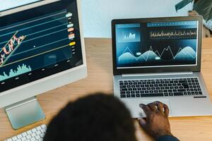 A person is using a laptop and a monitor with a graph on it photo