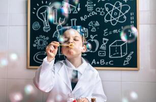 A young boy in a lab coat blowing bubbles photo
