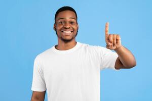 First. Black Guy Showing Number One With Finger Smiling To Camera Posing On Blue Background. Studio Shot photo