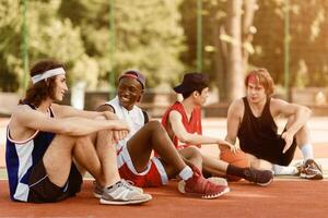 Multiracial basketball team taking break after their game at outdoor arena, empty space photo