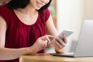Useful App. Young Asian Girl Using Smartphone And Laptop While Sitting In Cafe, Browsing Internet Or Shopping Online, Copy Space photo