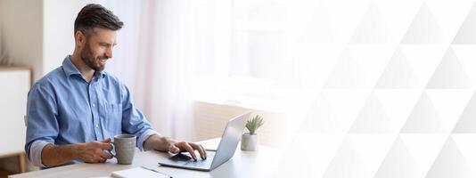Home Office. Smiling Freelancer Man Checking Emails On Laptop And Drinking Coffee, Enjoying Working Remotely, Copy Space photo