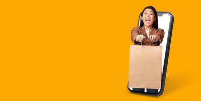 A happy customer with a big smile holds a shopping bag while interacting with an online store on a large smartphone screen. The bright background enhances the shopping experience. photo