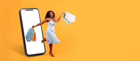 A shopper joyfully holds colorful shopping bags while interacting with their smartphone. The large device displays a web store interface against a vibrant yellow background. photo