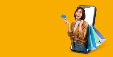 A buyer engages in online shopping using a smartphone, showcasing their excitement. They hold a credit card while colorful shopping bags peek from the device, set against a bright background. photo