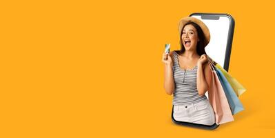 A happy buyer interacts with a smartphone displaying a web store, holding shopping bags and a payment card. This showcases modern commerce and the convenience of digital shopping. photo