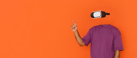 User explores virtual reality using modern goggles, gesturing as if interacting with digital elements. The vibrant orange background highlights the cutting-edge tech experience. photo