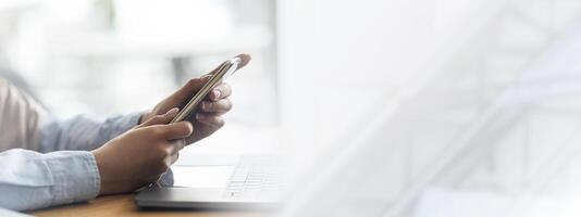 Woman hands holding mobile phone and using laptop, freelancer working at cafe, cropped, copy space. Unrecognizable lady using smartphone, having break form job, chatting with friends photo