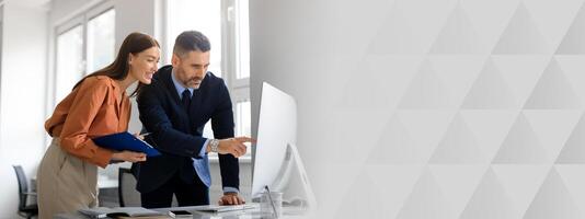 Successful caucasian man and woman coworkers in formal outfits working with computer, having conversation and discussing new project or startup at office, copy space photo