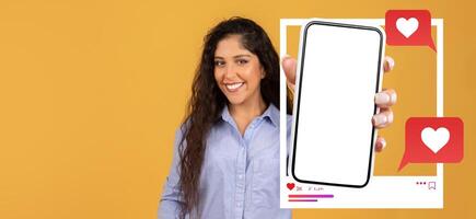 A social media influencer smiles while holding a smartphone with a blank screen, surrounded by chat bubbles featuring hearts. This setting emphasizes online interaction and digital communication. photo