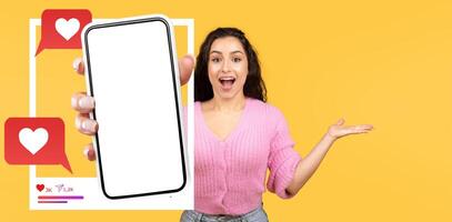 An influencer holds a smartphone displaying a blank screen, excitedly gesturing with her other hand. The vibrant yellow background enhances the lively atmosphere of online interactions. photo