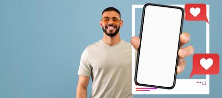 An influencer is smiling while holding a smartphone featuring a blank screen. The background is a solid color, emphasizing the vibrant interaction with followers online through social media platforms. photo